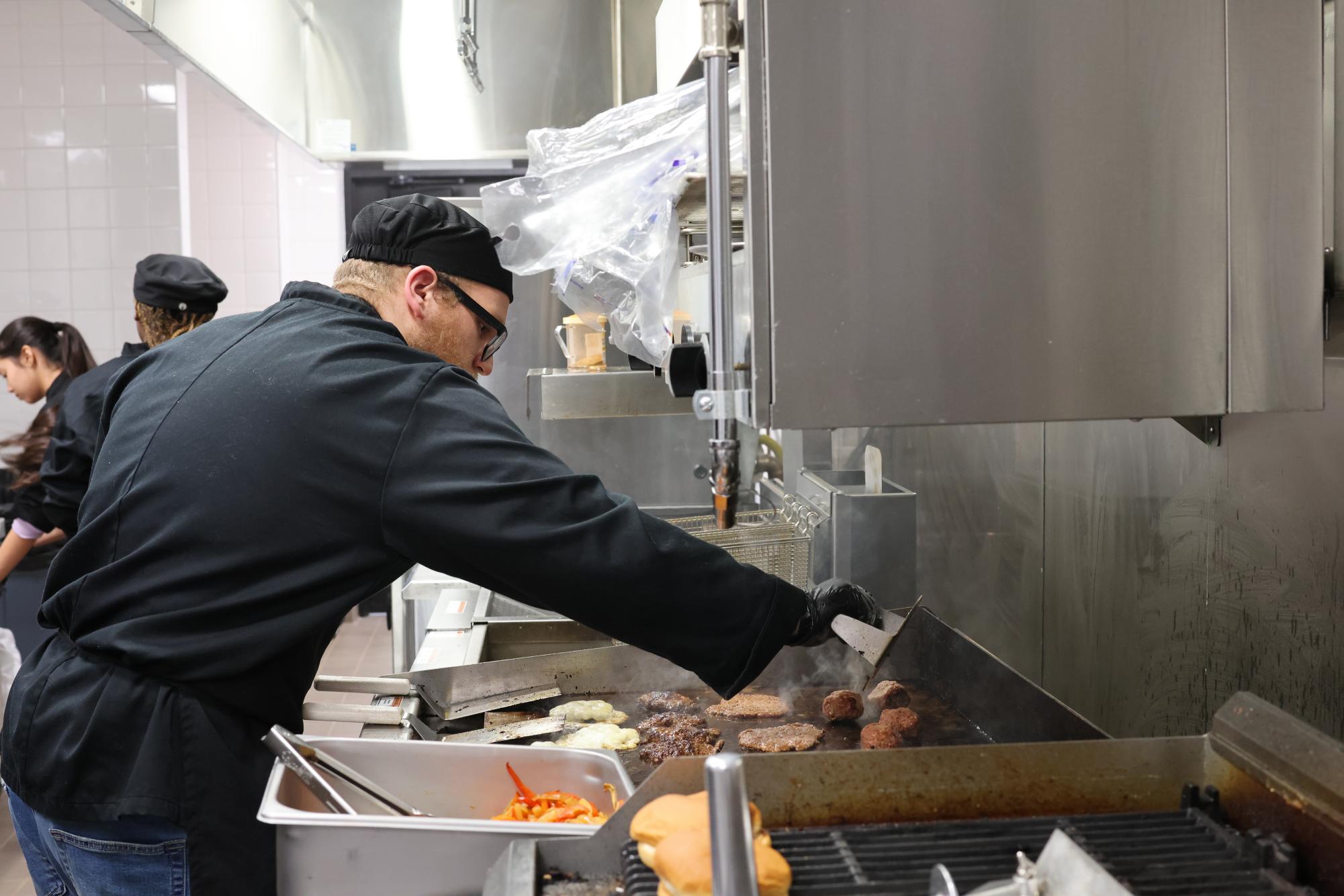 Cooking them to perfection, senior Frank Upchurch makes the hamburger patties for a past smashburger lunch menu. Each burger was served with a side of fries. "It's very eclectic," counselor Lori Heusinger said. "Sometimes it's Italian, sometimes it's Americano. I mean it just changes, and it is always good."